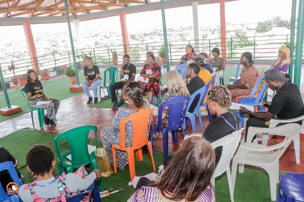 A Wellness 360 support circle meeting under an open-air pavilion, participants seated in a ring of chairs