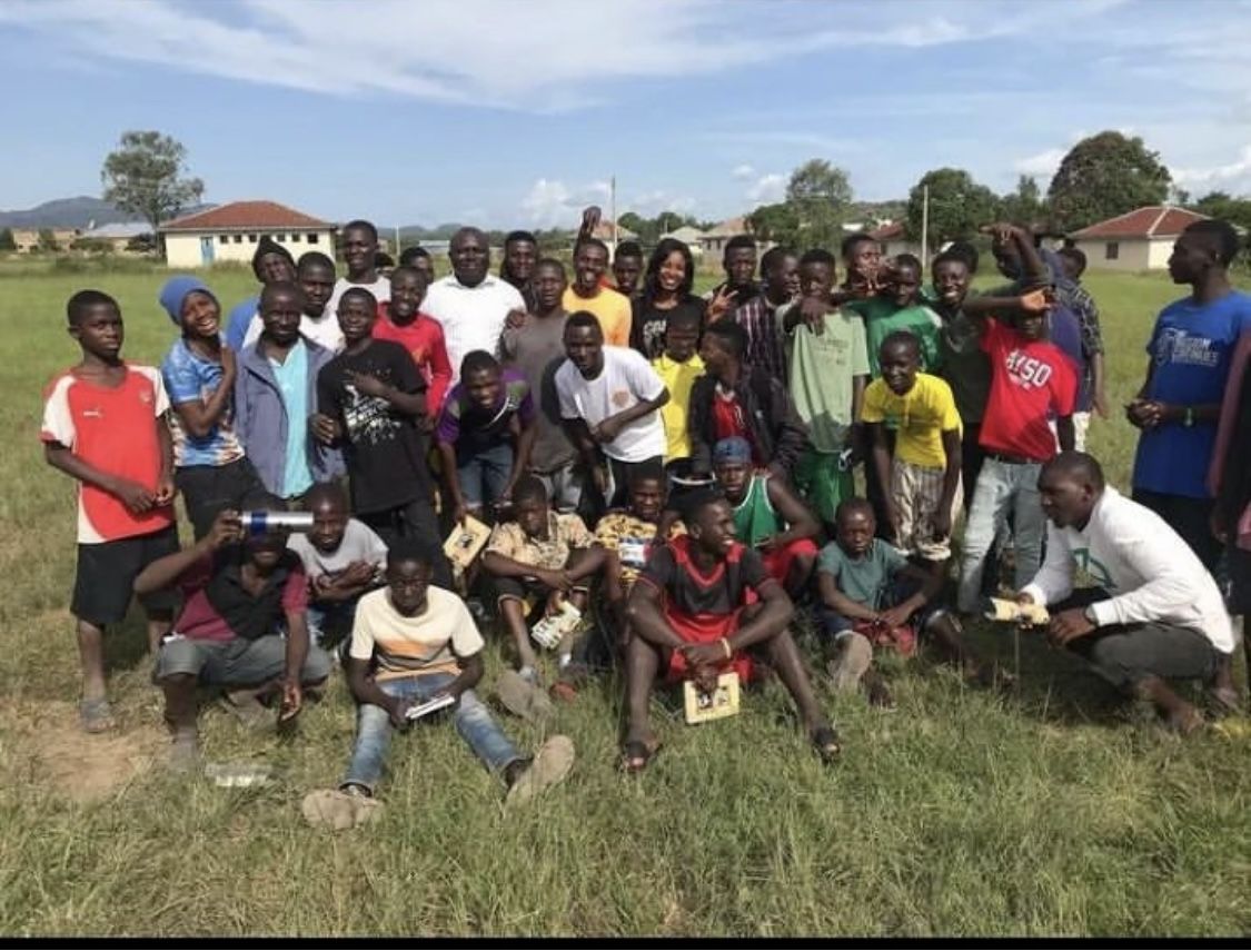 A large community group gathered outdoors on a field after a programme