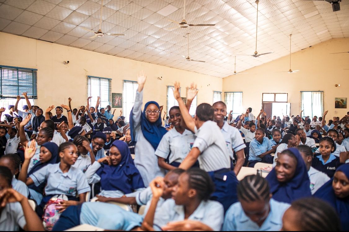 A hall full of students raising their hands during an awareness session